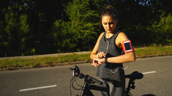 Woman Riding a Bike with a Smartwatch Heart Rate Monitor. Smart Watch Concept