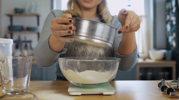 Young Beautiful Woman Weighs the Flour