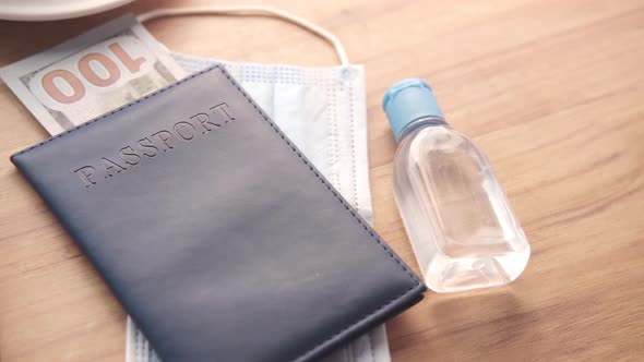 Protective Mask Hand Sanitizer and Blue Color Passport on Table