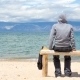 Man or Woman Is Sitting in a Hoodie on the Beach. Back View - VideoHive Item for Sale