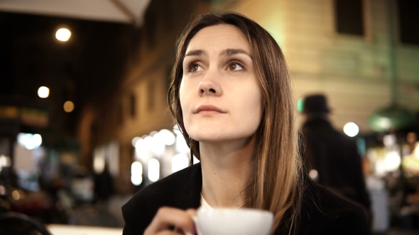 Young Beautiful Woman Sitting in the City Centre in Cafe, Holding Cup and Drinking Coffee in the
