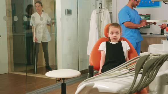 Little Girl Patient Waiting Pediatric Stomatologist Woman Sitting in Dental Chair