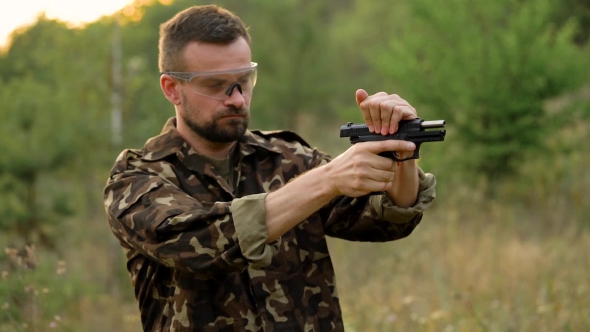 Young Man in Camouflage Shooting From a Gun alt