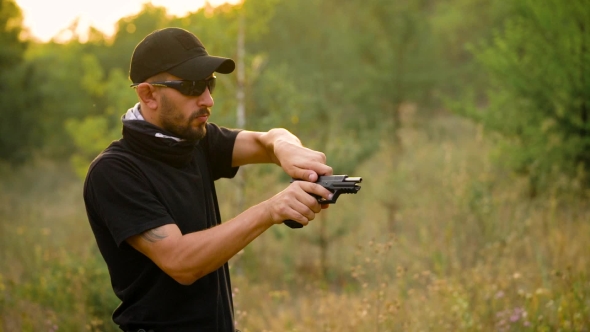 Young Man in Camouflage Shooting From a Gun