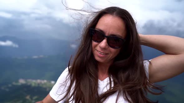 Portrait of a Woman with Dark Glasses on the Background of a Mountain Valley. the Wind Blows Her