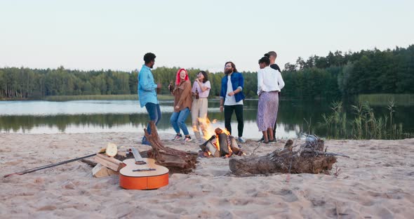 Friends are Dancing Party on the Beach By the Lake Until Morning Early Dawn Campfire is Burning