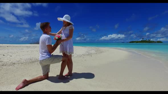 Two lovers relax on tropical island beach lifestyle by blue water with clean sandy background of the