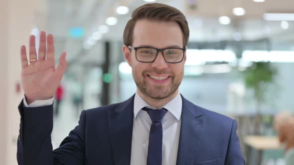 Portrait of Welcoming Businessman Waving at the Camera