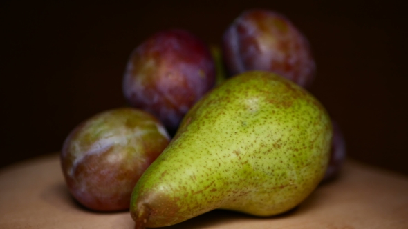 Portion of Plums and Pear at Wood Rotating Plate