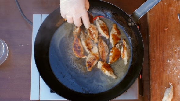 Ptting Salt and Pepper To Dumplings Fried in a Pan in Oil