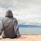 Man or Woman Is Sitting in a Hoodie on the Beach, Back View - VideoHive Item for Sale