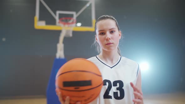 Portrait of a Young Female Basketball Player Holding a Ball in Her Hands and Looking at the Camera