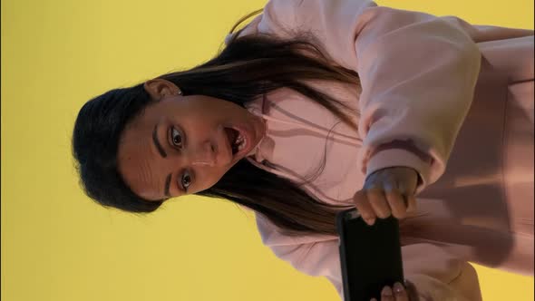 Pleasant-looking Black Girl Playing Games on Smartphone on Yellow Background.