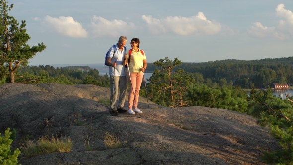 Elderly Active Couple on the Rock with Sunrise, Sunset 