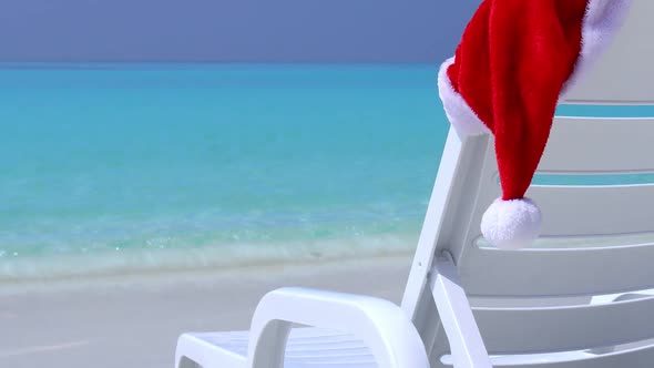 Santa Claus Hat on Sunbed Near Tropical Calm Beach with Turquoise Sea Water and White Sand