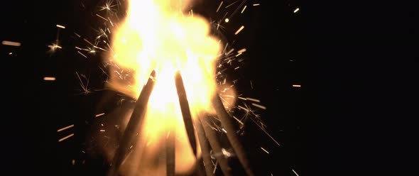 Sparklers burning down in the dark background in slow motion. 