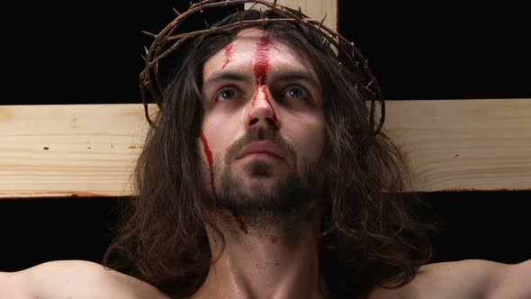 Crying Jesus Christ With Bleeding Face Looking at Camera, Crucifixion on Cross