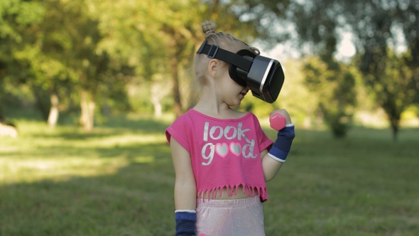 Athletic Child Girl in VR Headset Helmet Making Fitness Workout Exercises with Dumbbells in Park