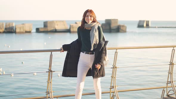 Young Beautiful Woman Walks and Enjoys the Sea on a Warm Winter Day