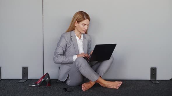 Tired Business Woman Without Shoes Feels Pain in Legs Using Laptop