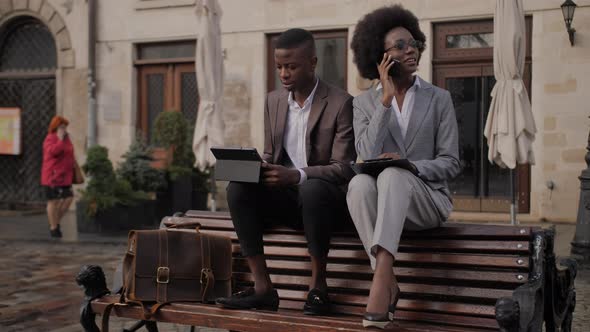 African Man Working on Tablet While Woman Talking on Mobile