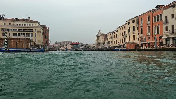 Water surface pov of Venice seen from ferry boat on Canal Grande with Ponte Degli Scalzi bridge in b