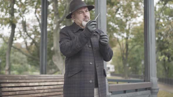 Portrait of Concentrated Spy Examining Test Tube with Poison in Spring or Autumn Park. Focused
