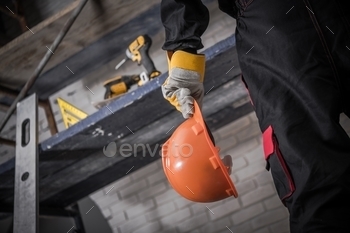  Safety Hard Hat in Hand. Scaffolding with Tools in Background.