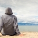 Cinemagraph - Man or Woman Is Sitting in a Hoodie on the Beach. Back View - VideoHive Item for Sale