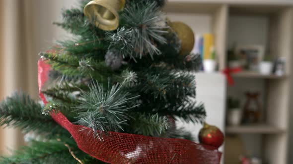 Woman decorating Christmas holiday tree at home with red balls, close