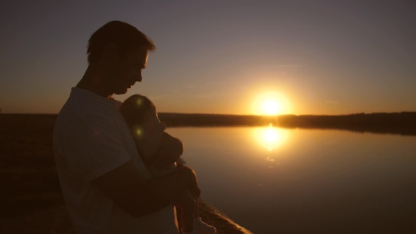 Father Circling in Arms of Small Baby at Sunset Evening Sun. .