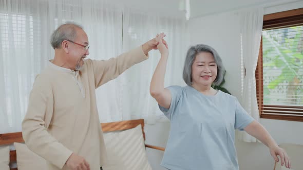 Asian happy Senior elderly Couple stay at home, spend leisure time dancing together in living room.