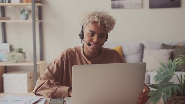 Dark Skinned Female Wears Headset Conference Video Calling in Home Office