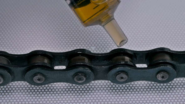 Man Lubricates the Chain,from the Syringe Drips Oil on the Chain Links