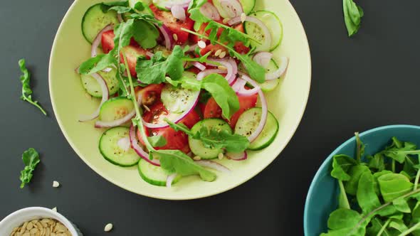 Video of fresh salad with green leaves and bowls with salad leaves and nuts on grey background