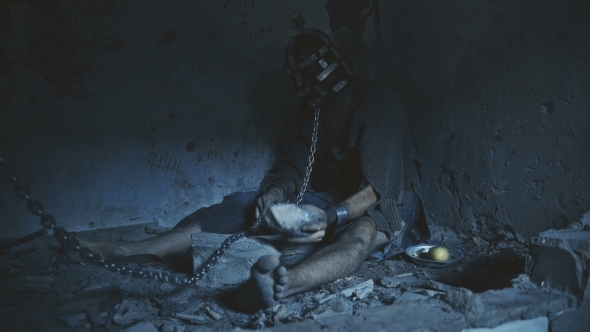 Prisoner in Chains Trying To Cut the Chain with a Rock To Escape