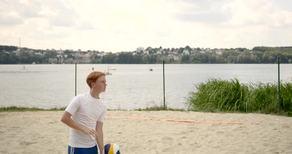 Teenage Boy Playing Volayball Oon a Beach By Lake