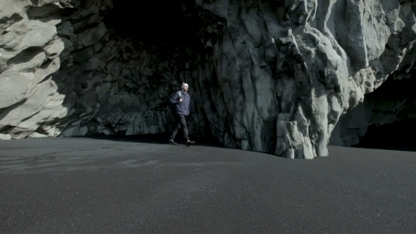 Young Bearded Man Standing Alone in a Cave of Iceland.