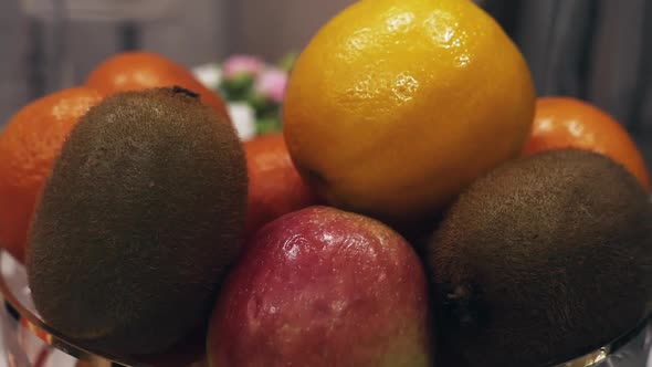 Fresh ripe citrus fruits, apples and kiwi in a plate close-up