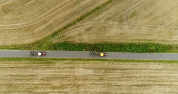 Aerial View of Tractor Passing Road. Agricultural Tractor Workin on Field