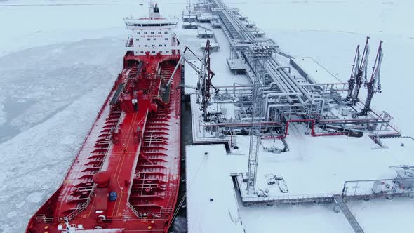 A Large Red Ship Stands at the Pier in the Port and Refuels in Winter