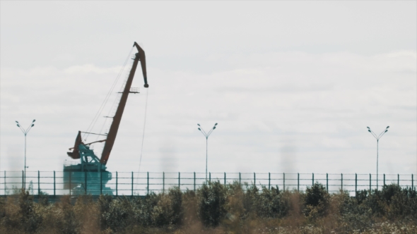 Large Metal Cargo Crane Over Busy Highway on Hot Summer Day