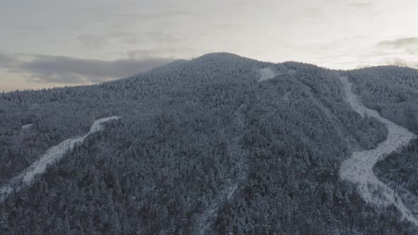 Flying towards the snow dusted peak of an abandoned ski mountain at sunset AERIAL