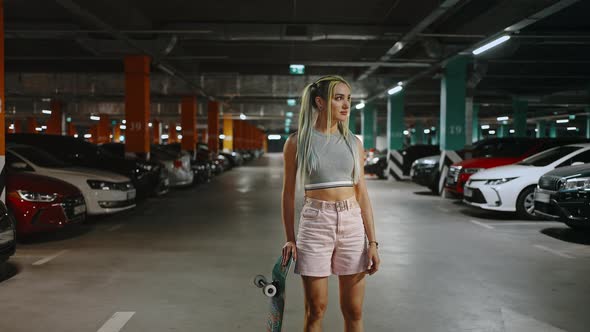 Portrait of Trendy Lady with Colorful Hairstyle Posing at Underground Parking with Skateboard