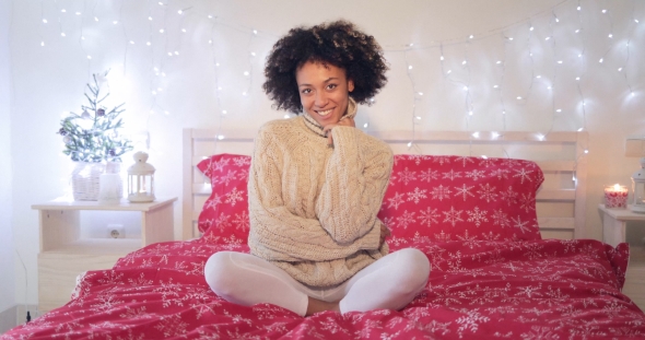 Smiling Confident Young Woman Sitting on Her Bed