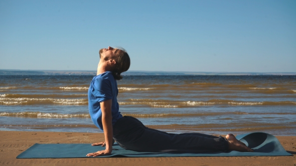 Young Man Practicing Yoga Ln the Beach. Upward Facing Dog