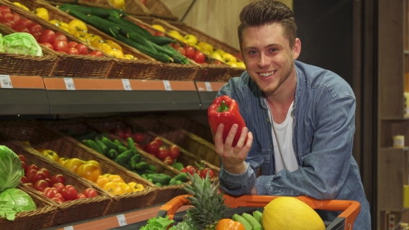 Man Examines Bell Pepper at the Supermarket