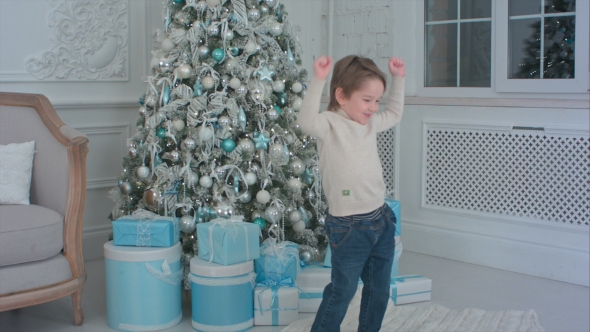 Happy Little Boy Dancing Next To the Christmas Tree and Presents