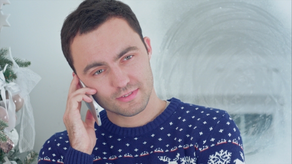 Young Man in Christmas Sweater Talking on the Phone