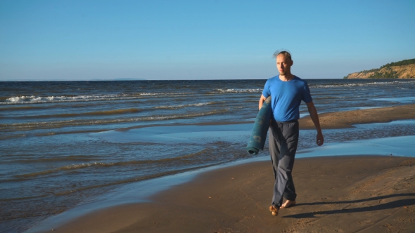 a Man with a Yoga Rolls Walking on the Beach